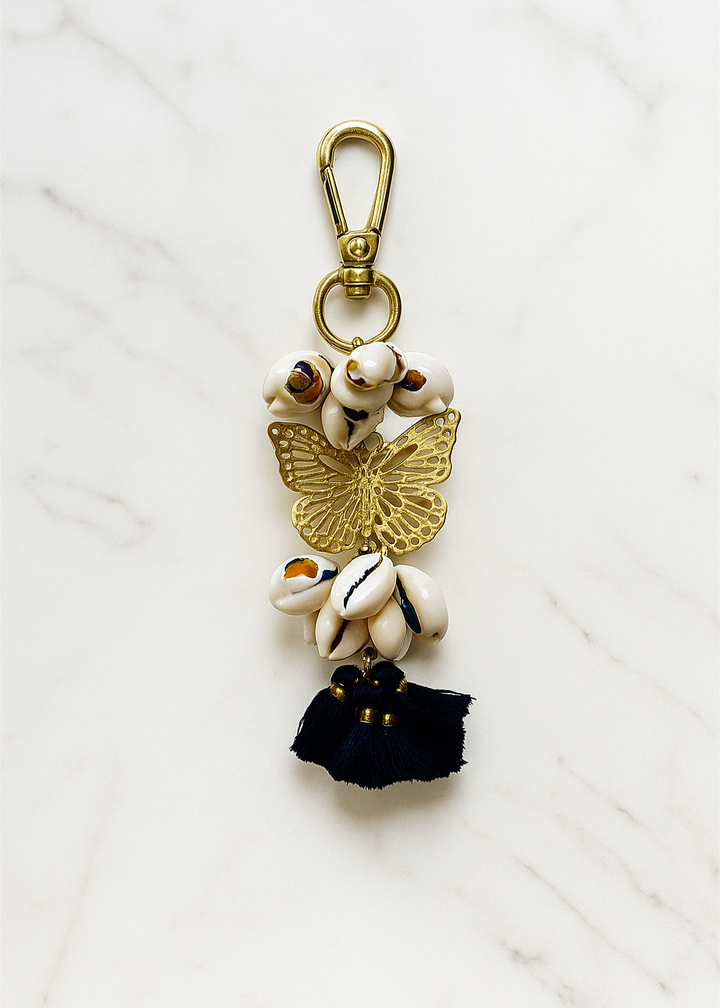 Decorative keychain with butterfly, shells, and black tassel on a white background