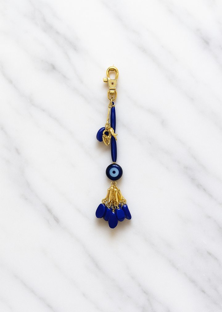 Blue evil eye charm with gold accents on a white fabric background