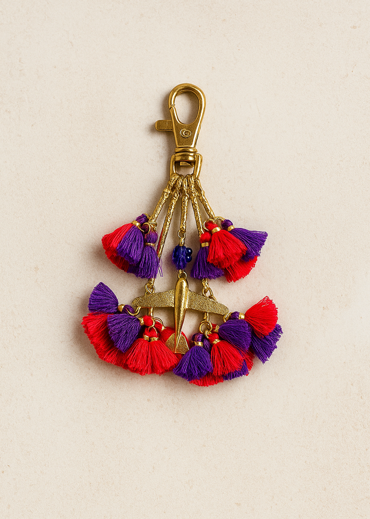 Colorful tassel keychain with a gold clasp on a beige background