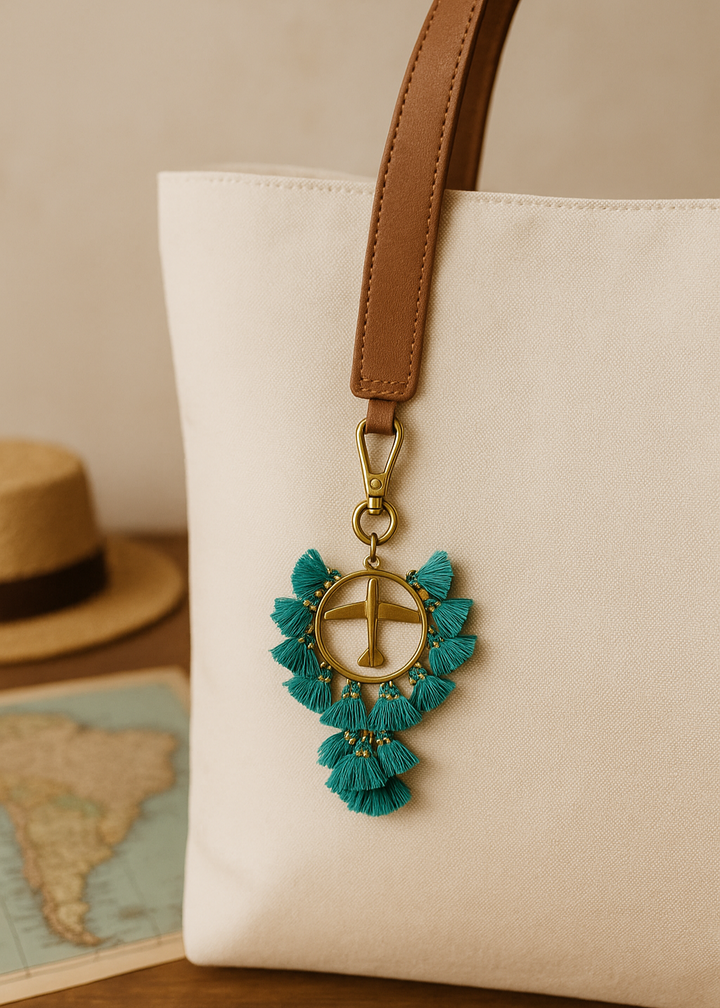 Decorative keychain with tassels attached to a beige bag on a wooden surface.