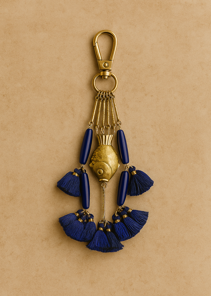 Decorative keychain with blue tassels and gold accents on a beige background
