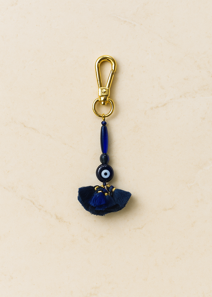 Navy blue keychain with a gold clasp on a beige background