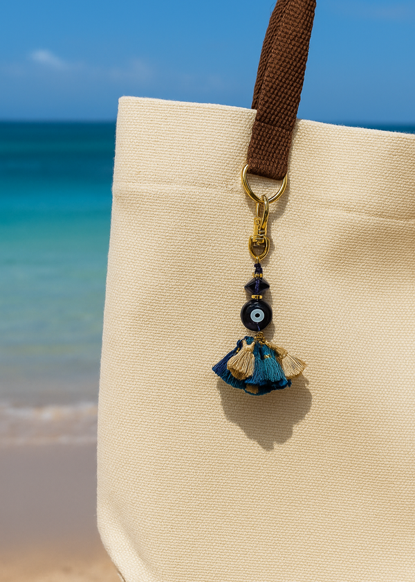 Beige tote bag with a decorative keychain on a beach